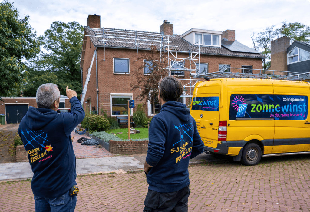 Monteurs kijken en wijzen naar huis waar geïnstalleerd wordt